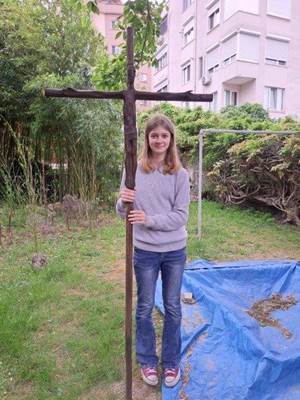 A child holding a large wooden cross

Description automatically generated