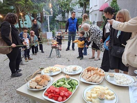 A group of people holding food and a couple of people standing around

Description automatically generated