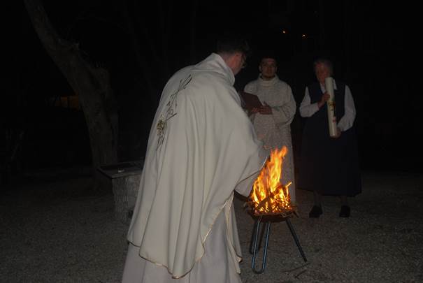 A group of people standing around a fire

Description automatically generated