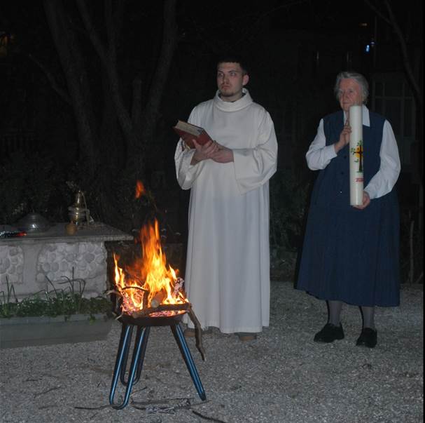 A person in a white robe standing next to a fire

Description automatically generated