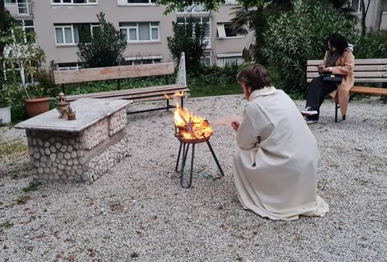 A person sitting in a white robe cooking food on a small fire pit

AI-generated content may be incorrect.
